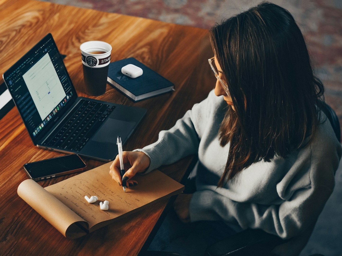 a woman sitting at a table writing on a piece of paper